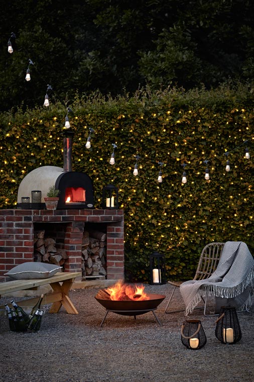 Mobil tűzrakó teraszon éjjel, hangulatvilágítással és kemencével